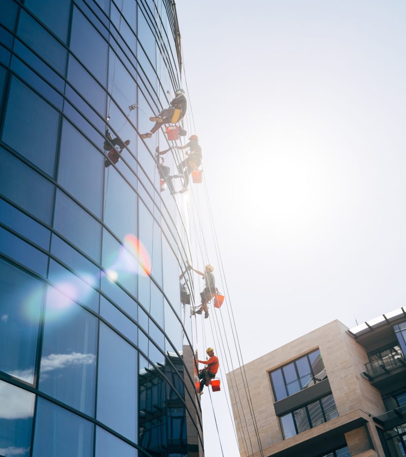 Outside of the building washing the glazing of the facade of a multi-storey building climbers clean windows, bottom view